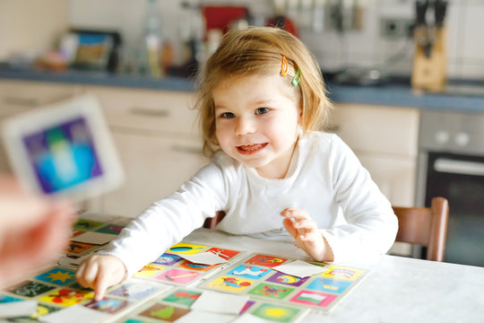 Adorable cute toddler girl playing picture card game with mother or father. Happy healthy child training memory, thinking. Development step and education of kid.