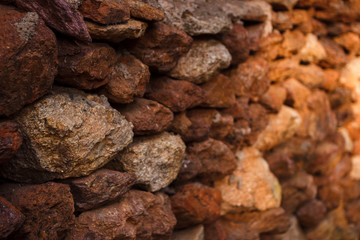 The wall of red stones illuminated by the sun. Masonry texture. Stone texture closeup