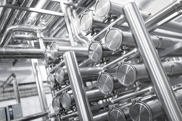 Steel water pipeline, chrome pipes, pipe lines in plant workshop. Industrial background