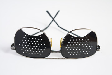 Black medical glasses with holes for vision correction on a white background
