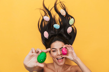 Pleased happy young woman lies isolated on yellow background over easter eggs.