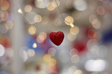 Love concept, heart shaped love symbol hanging in the air on bokeh background from garland