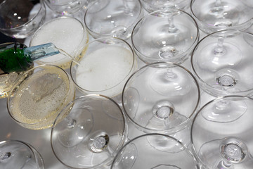 Closeup of the hand of the waiter pouring champagne into glasses