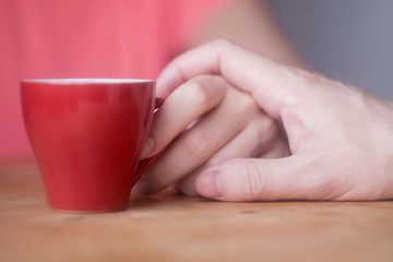 Fototapeta na wymiar male hand touches female hand with a cup of coffee flirting, courting, love