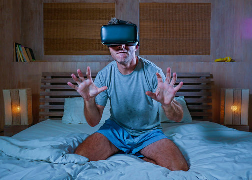Fototapeta young excited and aroused man at home wearing 3d virtual realty goggles having fun on bed playing alone with internet cyber sex VR simulator in sexual illusion and desire