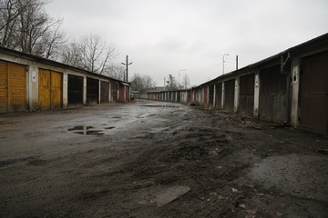 Old, neglected, ruined garages. Muddy, holey, uneven road with puddles. Winter, autumn landscape in the city. Wrocław, Wroclaw, Breslau.Lower Silesia, Dolny Śląsk. Polska, Poland, Polen. 