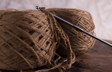 Wines and a whittling hook, which lies on top of brown yarn for knitting and vintage book