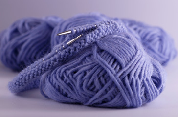View of balls of blue knitting yarn, knitting needles and knitted loops lie on the table. Knitting...