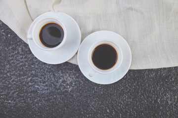 Two white cups of espresso on grey grunge background.