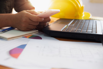 Hands of architect woman using mobilephone on working desk.