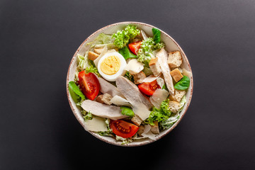Homemade Caesar Salad with Chicken, Chicken Egg, Cherry Tomatoes, Parmesan Cheese, Lettuce Mix and Caesar Sauce. dish on gray background. Top view, copy space