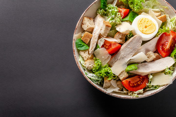 Homemade Caesar Salad with Chicken, Chicken Egg, Cherry Tomatoes, Parmesan Cheese, Lettuce Mix and Caesar Sauce. dish on gray background. Top view, copy space