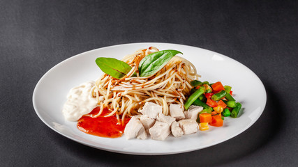 The concept of Italian cuisine. Homemade pasta spaghetti with chicken, vegetables, white and red sauce. Dish on a gray background. Top view, copy space