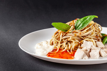 The concept of Italian cuisine. Homemade pasta spaghetti with chicken, vegetables, white and red sauce. Dish on a gray background. Top view, copy space