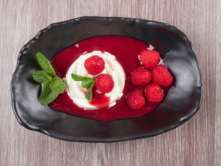 Vanilla bean pannacotta with raspberry coulis, fresh raspberries, and mint leaves