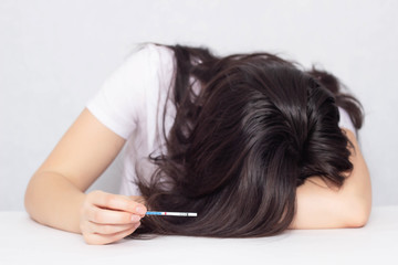 The girl cries at the table and holds in her hand a test for pregnancy is negative, infertility, fertility