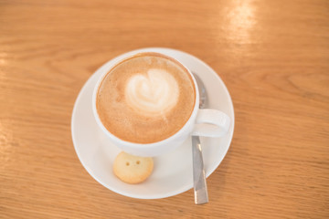 Cup of coffee to go on the wooden table with latte art. Street coffee. white cup of cappuccino. Trendy toning. Minimal composition, hipster vibes. Top view, flat lay copy space for your text.