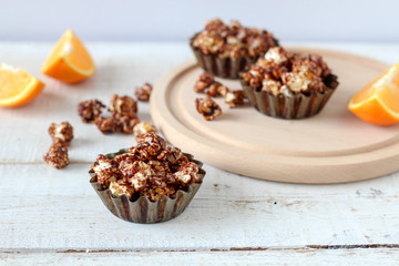 Chocolate popcorn in rustic baking molds on a wooden table