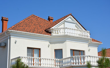 Modern luxury house with clay roof tiles, rain gutter, outdoor lighting,attic windows , balcony.