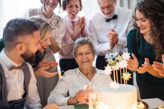 An elderly woman with multigeneration family celebrating birthday on indoor party.