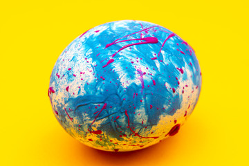 Blue handmade Easter egg on a yellow background. Religious traditional holiday.