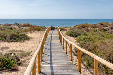 Wooden pathway over dunes and pines at beach in Punta Umbria, Huelva. Los Enebrales beach