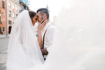Naklejka premium Happy wedding couple. Groom and bride kissing in the middle of the street in Prague, Czech Republic. Close up