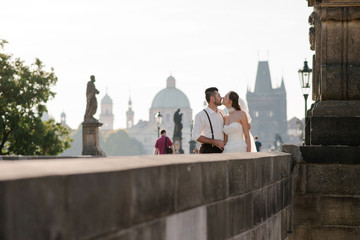 Happy wedding couple of groom and bride kissing while walking on the Charles bridge in Prague. Czech Republic