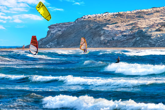 Two windsurfers and kiteboarder ride on Prasonisi beach (Rhodes, Greece)