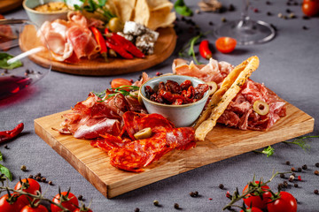 Italian food. Assortment of appetizers for a large company in a restaurant. Different types of smoked meat, sausages and cheeses. a glass of cool wine.
