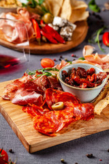 Italian food. Assortment of appetizers for a large company in a restaurant. Different types of smoked meat, sausages and cheeses. a glass of cool wine.