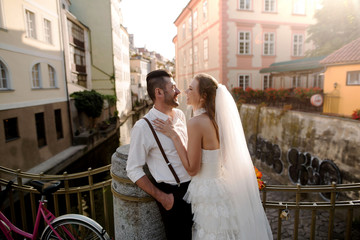 Happy wedding couple of groom and bride kissing and laughing in the middle of the street in Prague,...