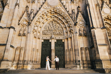 Wedding couple of groom and bride standing near the beautiful cathedral in Prague, Czech Republic