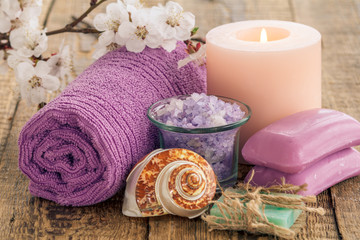 Obraz na płótnie Canvas Sea salt in glass bowl with towel, sea shell, soap and burning candle with flowering branch of apricot tree.