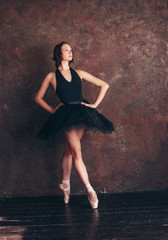 Ballet dancer ballerina in beautiful black dress tutu skirt posing in loft studio