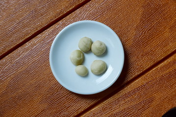 Top view of macadamia nuts in bowl on wooden background.