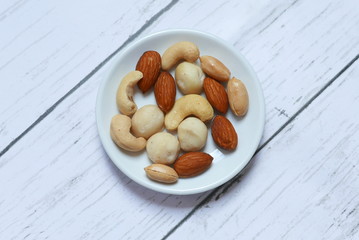 Top view of macadamia,cashew,almond and peanuts nuts in bowl on wooden background.