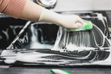 cleaning the sink from the ceramic coating of artificial stone with a foam agent in gloves. kitchen cleaning