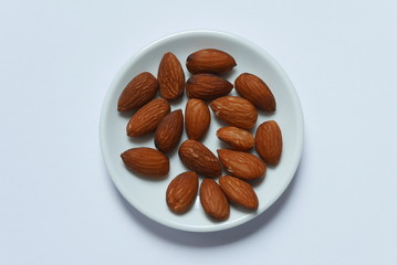 Top view of almonds in a bowl on white background.