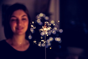 Happy girl is holding a sparkler at Christmas time