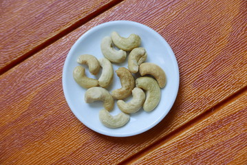 Top view of cashew nuts in bowl on wooden background.