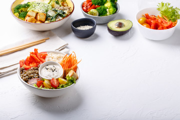 Buddha bowls  on white background. Colorful bowls with vegetables, healthy grains, and protein. Rice, lentils, tofu, tomatoes, sweet peppers, carrots, cashew sauce, sesame seeds. Copy space.