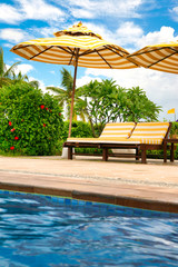 Empty lounge chairs by the crystal blue pool on Hainan Island.