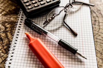 Marker pen, pen, eyeglasses and calculator on notebook. Close up, study, business and education concept. Image slightly blurred on foreground and background