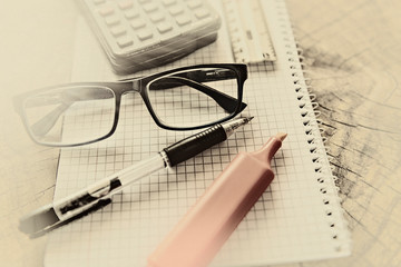Fototapeta premium Marker pen, pen, eyeglasses, ruler and calculator on notebook. Close up, study, business and education concept. Image slightly blurred on foreground and background