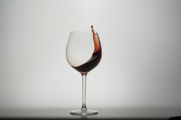 Splashing red wine in the glass. Isolated on white background