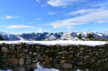Fototapeta na wymiar Winter landscape with snowy stone wall and mountains. Piornedo Village, Ancares Region, Lugo Province, Spain.