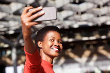 Fototapeta premium smiling young african woman taking selfie with cellphone camera