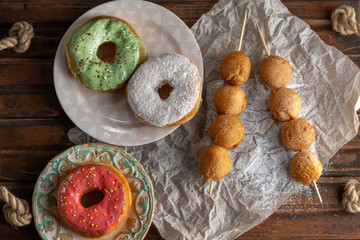 Cottage cheese balls and donutts on wooden skewers, lie on craft paper.