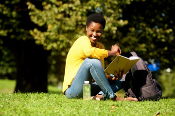 african american woman smiling with book in park